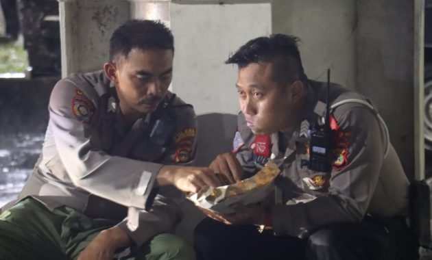 Dua Polisi Nikmati Nasi Bungkus Bersama di Dermaga Bakauheni Saat Hujan Deras