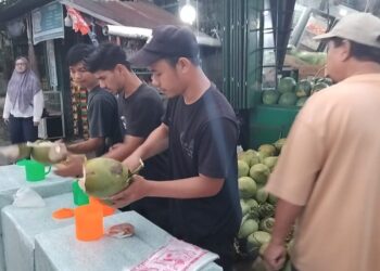 Muhammad siddiq beserta teman" nya sedang melayani pelanggan yang membeli air kelapa di, Jl. AMD, Banda Aceh. (TubinNews/Nurul Azkia)
